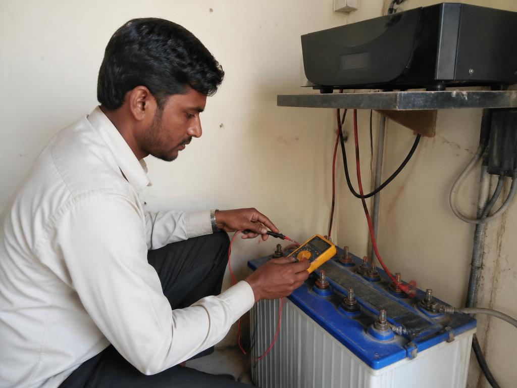Technician checking an inverter battery at a customer site in Gurugram